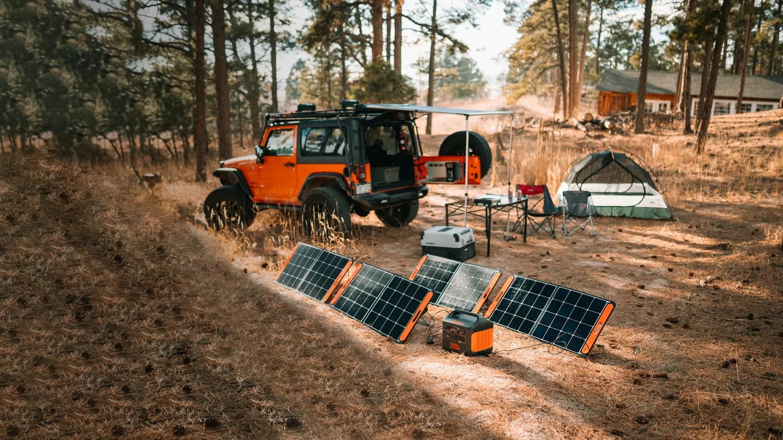 Jeep camp with a tent, solar panels and a portable power station at a pine forest campsite